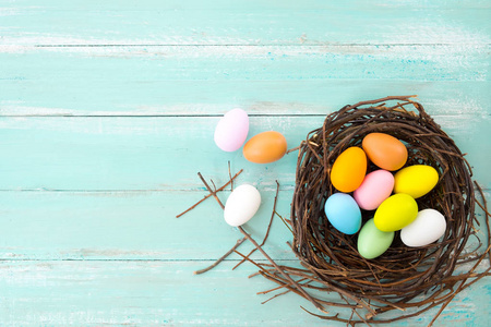 五颜六色的复活节彩蛋在巢与花在质朴的木板背景蓝色油漆。春节放假。老式的色调风格。顶部视图组合