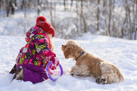 小女孩在雪地里玩着卡猎犬