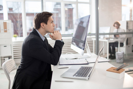 认真的雇员认真的年轻商人坐在办公桌前, 专注于财务分析照片