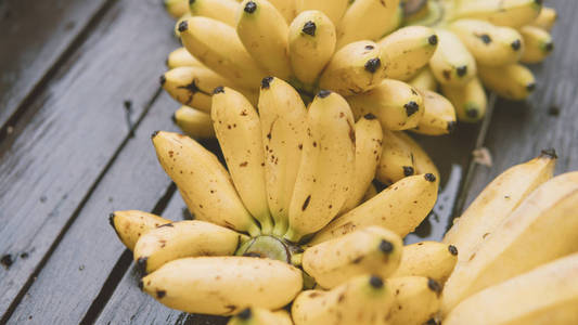 一堆成熟的香蕉躺在木桌特写的顶端。热带水果和饮食的水果在旅途中。亚洲热带水果