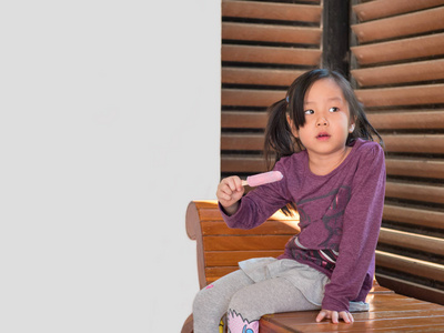 小亚洲女孩吃冰淇淋, 木纹条纹背景