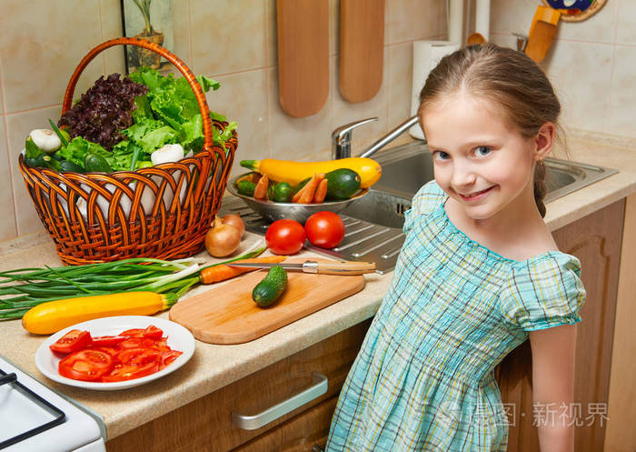 在家庭厨房做饭的儿童女孩.篮子蔬菜和新鲜水果在厨房内.健康食品概念