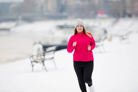 女孩穿着运动服，冬季在雪地上奔跑