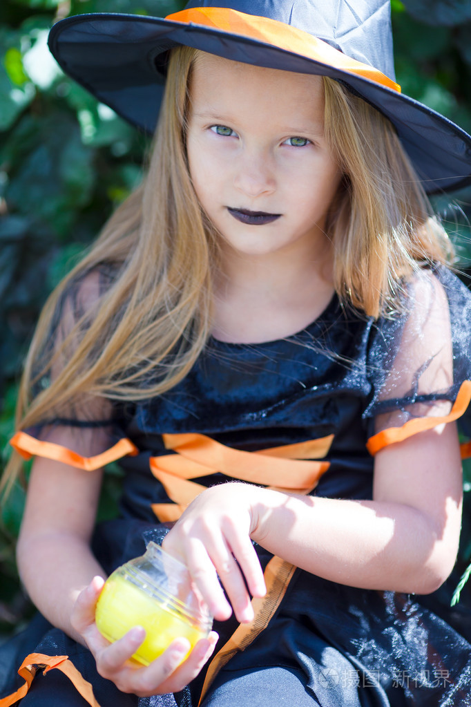 可爱的小女孩,在万圣节穿用扫帚的女巫服装的肖像