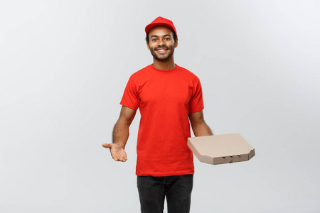 交付概念美国快乐非洲人的画像手指着一个披萨盒包。在灰色演播室背景下隔离。复制空间
