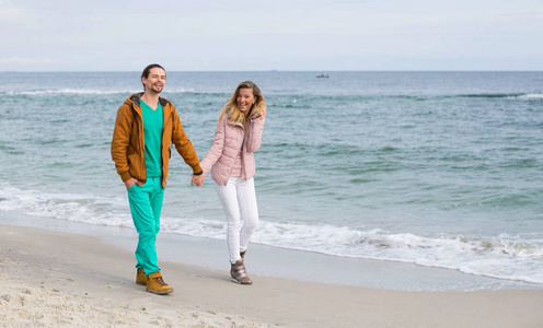 一对漂亮的年轻夫妇沿着海边散步。