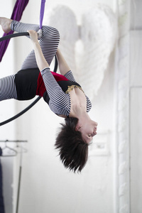 灵活的女子体操运动员倒挂在空中箍上
