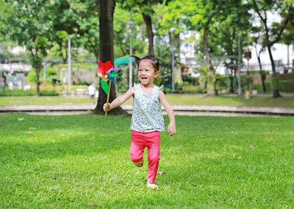 快乐亚洲儿童女孩与风力涡轮机在花园里