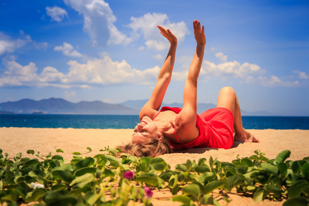 女孩在红色躺在沙子上升降机的双手靠近前景藤蔓