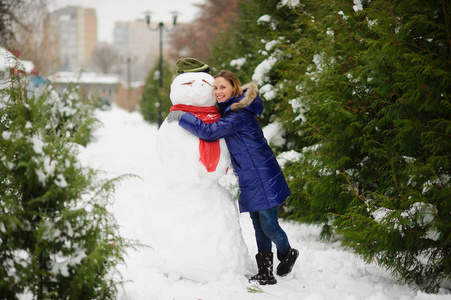 冰雪覆盖的公园。女孩调皮地拥抱大堆雪人