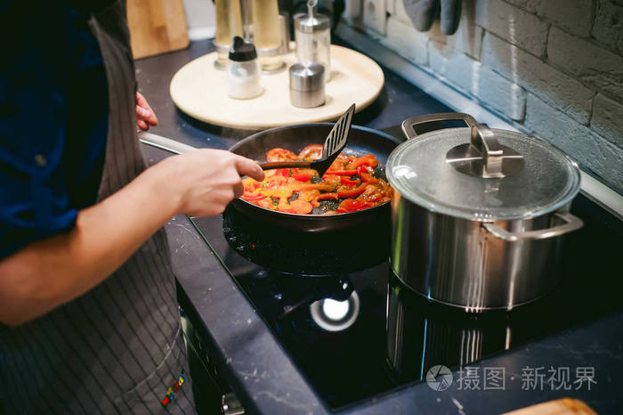 家庭主妇的女人准备在他厨房里的蔬菜和火腿煎蛋