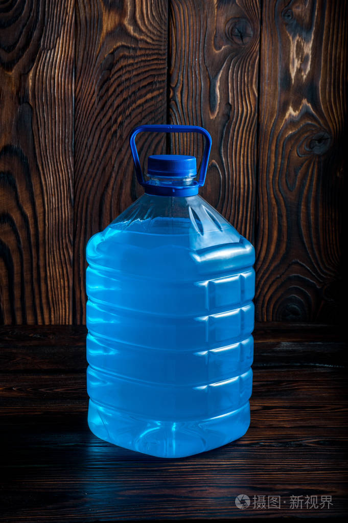 黑木背景上的大塑料蓝色瓶子