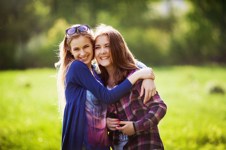 两个年轻女孩在公园拥抱在一起