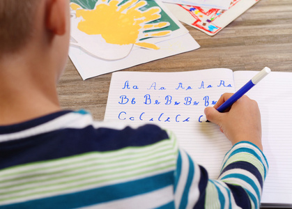 学校男孩写论文用铅笔写作字母表。刚出生的宝宝，做作业，教育理念