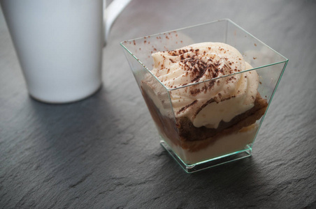 在玻璃和杯咖啡在黑板上的提拉米苏甜点