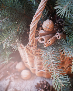 自然的圣诞装饰在篮子里。坚果，枞树，肉桂，松果上木制背景
