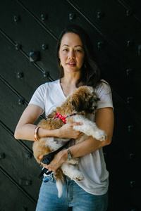 一个年轻的女孩和她的狗的肖像。泛亚洲女人很有魅力, 穿着随意, 带着她的 Tzuh 在怀里, 轻轻地微笑着。