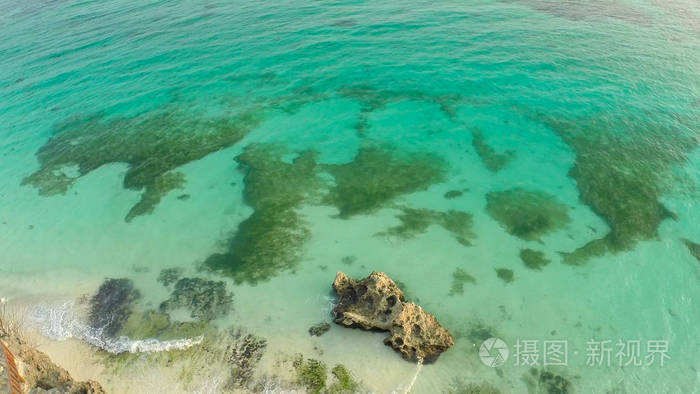 一个美丽的浅绿色海岸与珊瑚礁和一对情侣在阳台上方的海滩上.