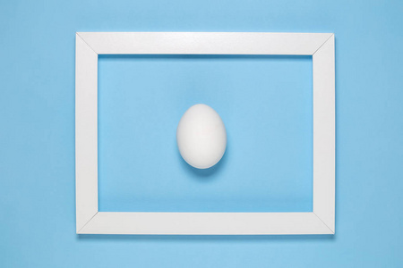 纯蓝色背景下的白鸡蛋和相框