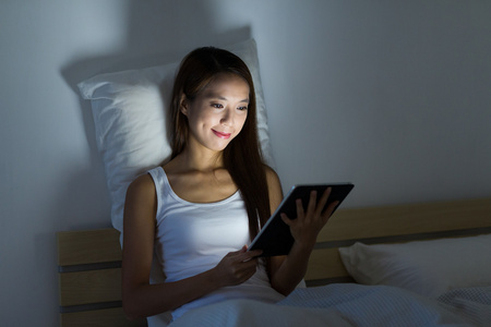 女人在床上的平板电脑阅读