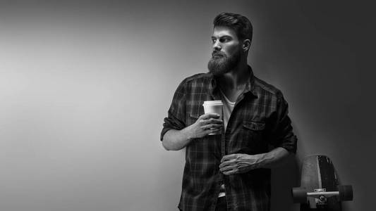 年轻的大胡子男子喝早晨咖啡的侧面视图