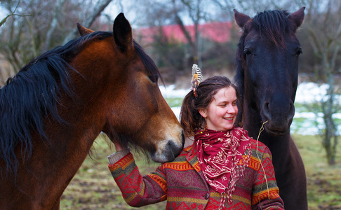 肖像女人和马在室外。抱着一匹马的女人，在她的头发有羽毛