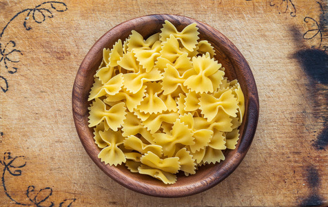 farfalle 通心粉面食在一个木碗上切割木板, 纹理背景, 在中心特写与顶部