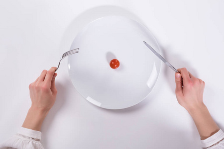 用刀叉把樱桃西红柿切在盘子上图片
