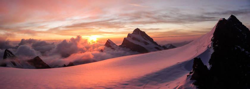 在阿尔卑斯山上的冰川和高山山峰上华丽的粉红色日出全景