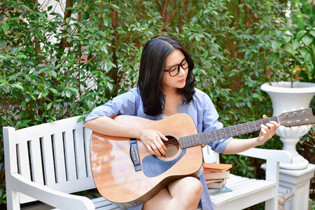 音乐概念。亚洲女孩在弹吉他亚洲女性放松