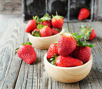 红色成熟的草莓在一个木碗在一个质朴的桌子上, 选择性的焦点
