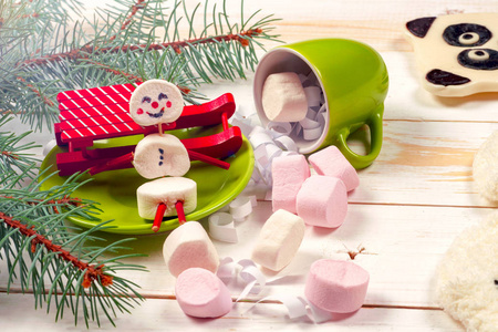 圣诞贺卡与有趣的棉花糖雪人在绿色杯，树