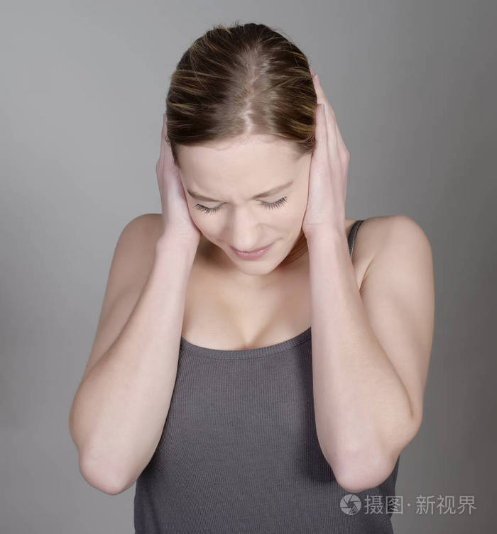 漂亮的年轻女子用手捂着耳朵