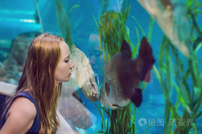 在隧道水族馆看鱼的年轻妇女