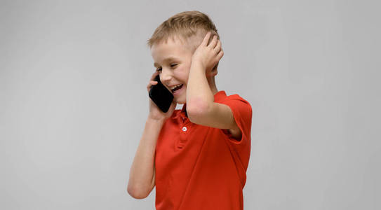 可爱的金发白种青春期男孩在明亮的 t恤显示不同的表达式, 而在工作室白墙上的电话交谈