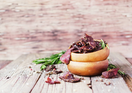 猛地肉 牛 鹿 野兽或干咸肉条在乡村的桌子，选择性焦点上的木碗