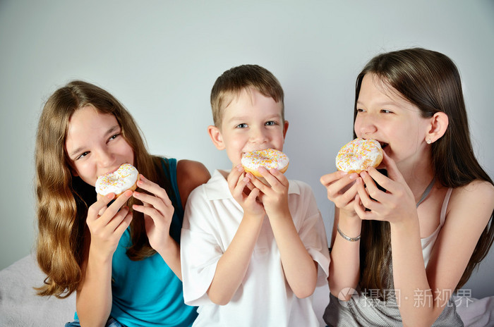 滑稽的男孩和两个十几岁的女孩吃甜甜圈.特写