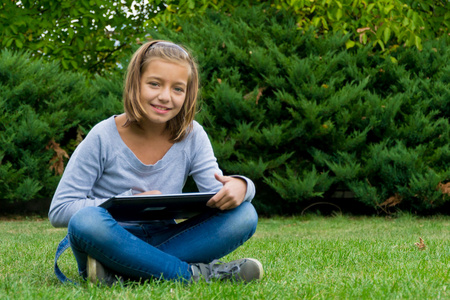 孩子坐在草丛中的笔记本电脑