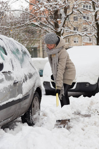 独立的女人在冬天铲雪