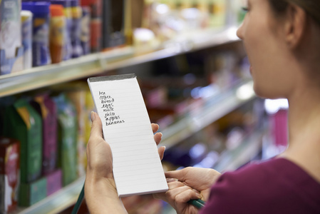 阅读购物清单在超市中的女人