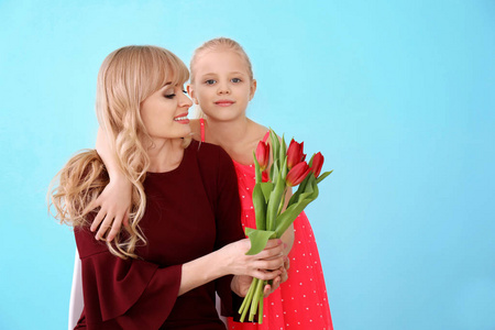 可爱的小女孩和她的母亲的肖像在彩色背景郁金香花束