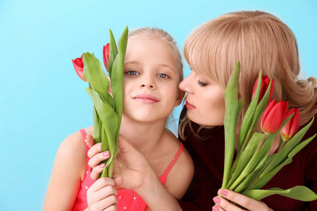 可爱的小女孩的肖像和她的母亲与郁金香在颜色背景