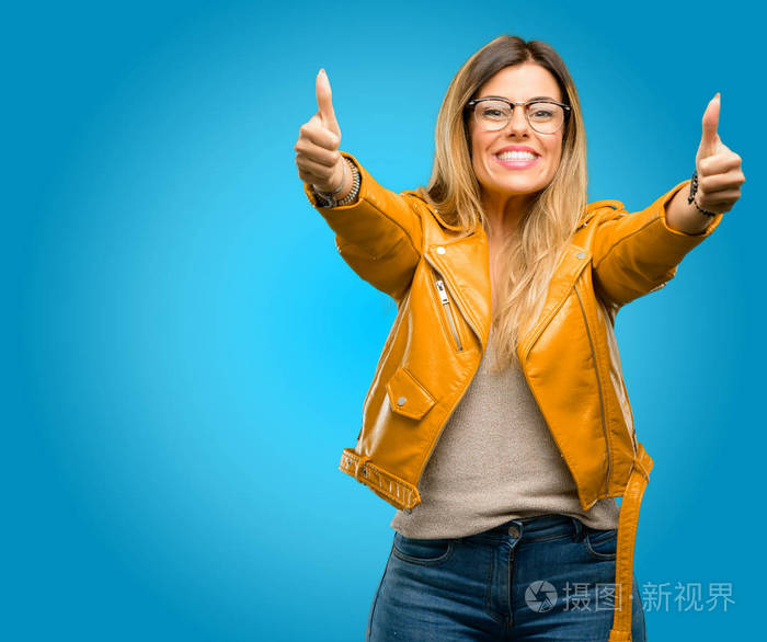 美丽的年轻女子站在高兴和积极与竖起大拇指同意一个大的微笑表示好