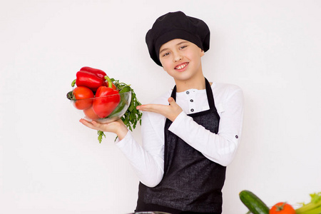年轻的男孩抱着一盘蔬菜与隔离