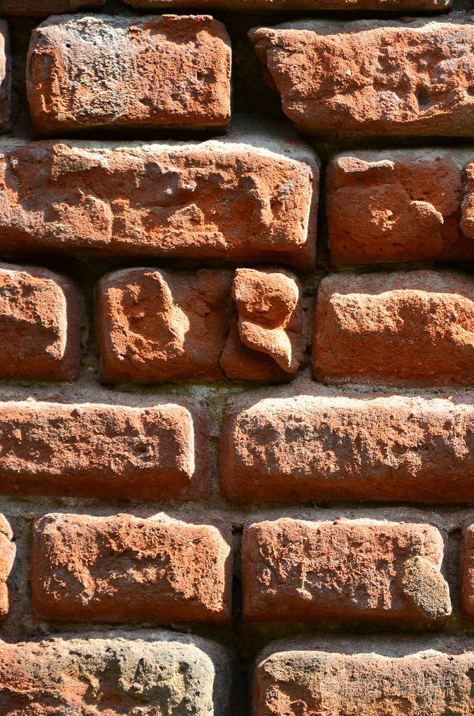 竖壁纹理的几排很旧的砖砌成的红色砖块.破碎和损坏的砖墙与捏的角落