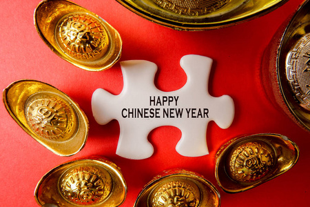金锭和白色拼图为农历新年喜庆装饰品在红色背景。汉字意味着运气, 财富和繁荣, 如图所示