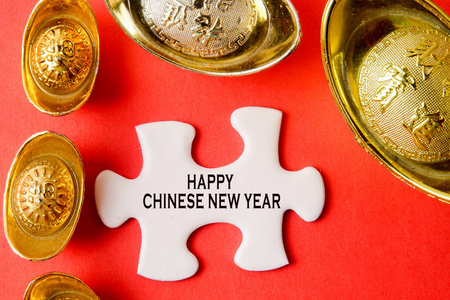 金锭和白色拼图为农历新年喜庆装饰品在红色背景。汉字意味着运气, 财富和繁荣, 如图所示