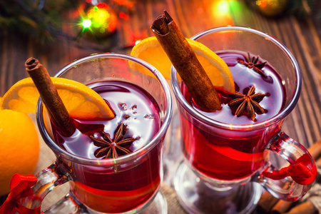 两杯，杯红热的饮料。甜酒木制背景与圣诞香料，橙片，关闭。圣诞香料酒。圣诞树，圣诞灯的分支