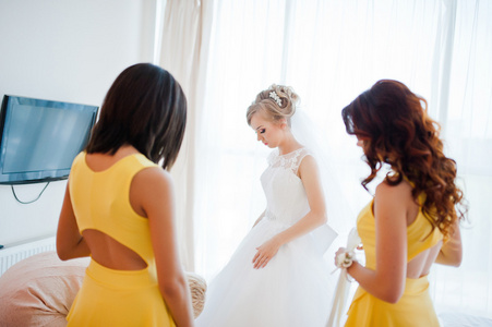 温柔金发新娘与伴娘在黄色的连衣裙