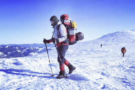 冬季到山中远足。在山里徒步旅行带着背包和帐篷雪的冬天